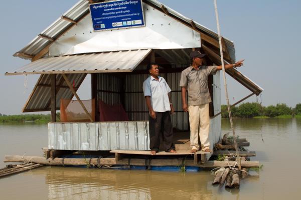 Two men stand on a small floating hut