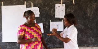 Volunteer in Rwanda. Mugirente Judith (left), a community health worker, taking part at the front of a a sexual reproductive health lesson with Niyonsaba Brown (right), a VSO national volunteer at Umutara School for Deaf children.