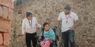 Volunteer with a girl with cerebral palsy, in a VSO provided wheelchair