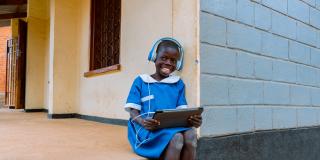 Smiling child sits on step with tablet