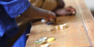 Child playing with educational resources on a school desk. Rwanda.