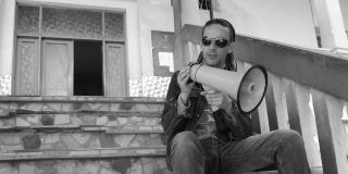 Darren Clark pictured here sat on steps with a megaphone, was a VSO volunteer and passionate about HIV and AIDS. Darren Clark pictured here sat on steps with a megaphone.