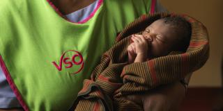 A VSO volunteer holding a newborn baby