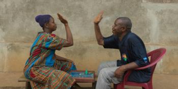 A married couple high five over a board game they are playing outside