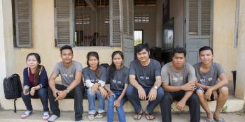 A team of ICS volunteers sit on the steps outside a building