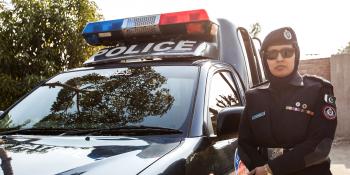 A female police officer stands next to her squad car