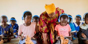 Volunteer Prisca helping student with tablet in a learning centre.