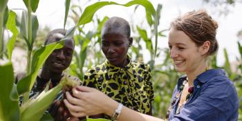 Randstad volunteer Jenny Hoevenagel looks at crops in a field next to members of a youth co-operative