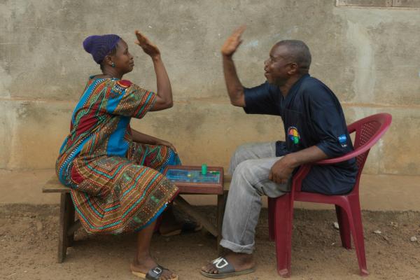 A married couple high five over a board game they are playing outside