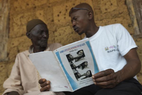 Two men sit and discuss a handbook about domestic violence