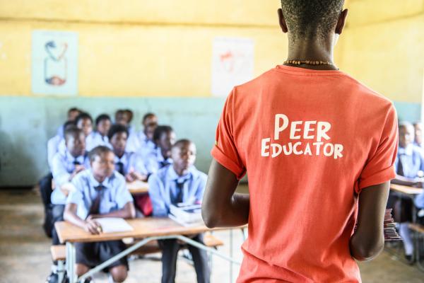 Peer educator Geofrey Mwaba stands at the front of a classroom to deliver a session