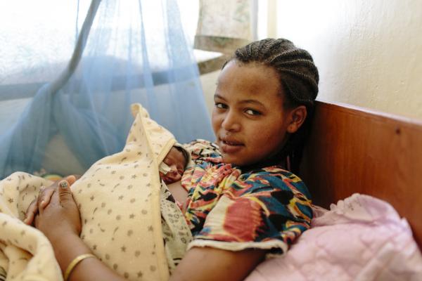 New mother Haimanot Haile rests as she holds her newborn baby against her chest