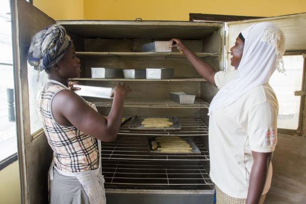 Juliana and Barkhisu place loaf tins onto large racks to cool down