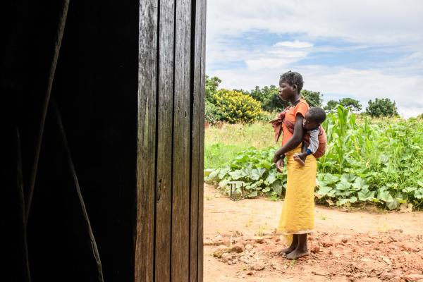 Sixteen-year-old Mary carries her baby on her back as she walks outside on the Zambian island of Mbabala.