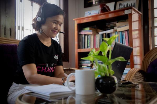 a woman sat at a laptop with a headset