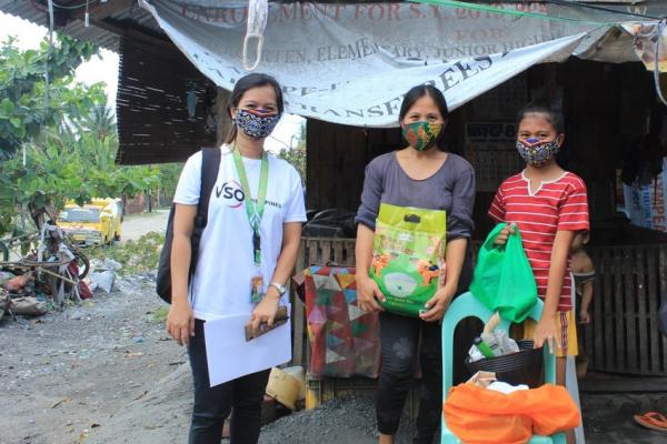 Three people in Cambodia standing outside, wearing masks and looking at the camera