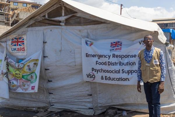 Sam by the tent where volunteers gather to coordinate food, education and psychosocial support