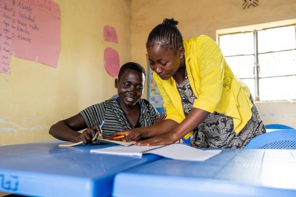 Teacher Alphonsina helps Jane (19 years old) with her classwork.