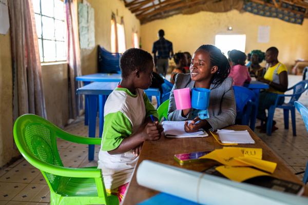 Clementia practises writing her letters with her teacher, Rael.