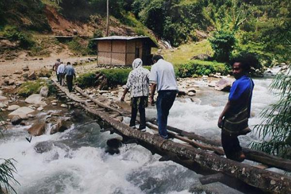 Peter crosses a river with locals in Papua New Guinea