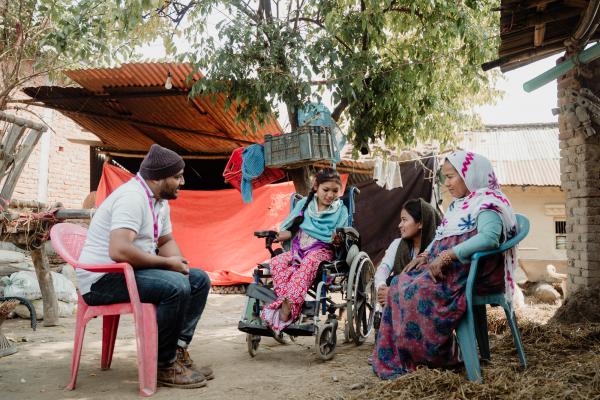 Volunteer talks to disabled girl and family