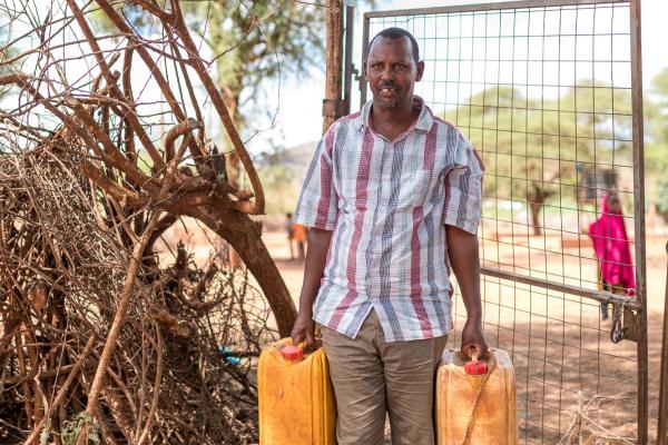 Man carrying jerrycans for water 