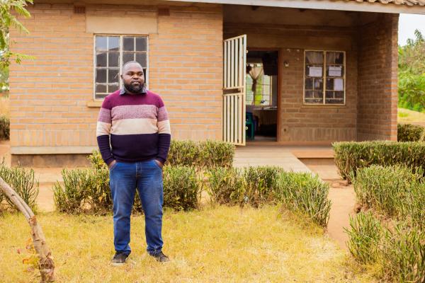 Atu standing outside a headteacher's office at a school.