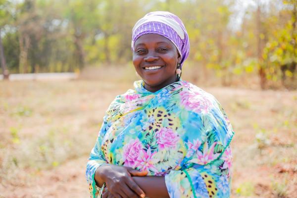 Fatima Zubairu stands proudly in a field during a demonstration day, showing farmers new farming techniques.