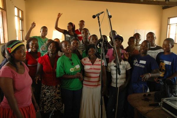 Recording a song in Mabote, Mozambique. a group of people in a room with microphones singing